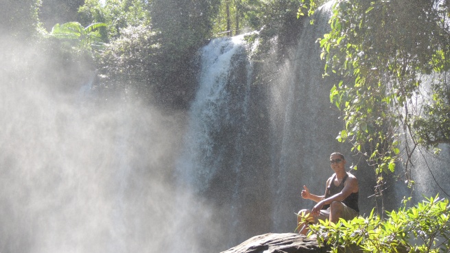 Bros my tuk tuk driver, available for you to book via this site, sat on a rock at the bottom level of the waterfall at Kulen Mountain in the national park.
